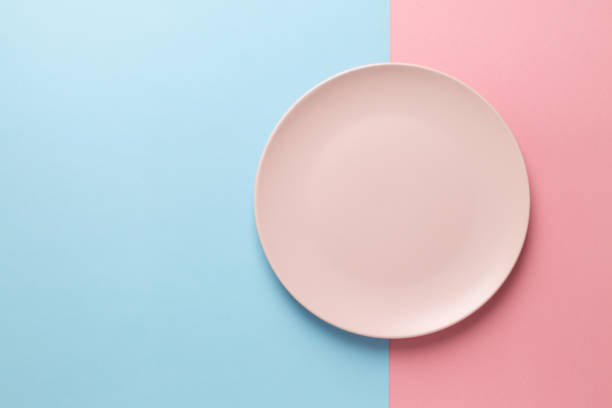 istock Empty pink plate on blue and pink pastel background 1221153628