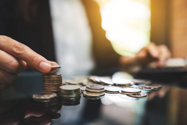 istock Businesswoman calculating and stacking coins on the table 1221155578