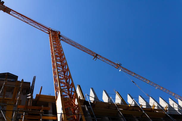 istock Construction crane towering over building site, construction of building still in progress, blue sky in background 1221155930