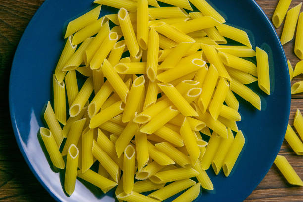 Pene Lisce pasta in blue plate on dark wooden background. Top views