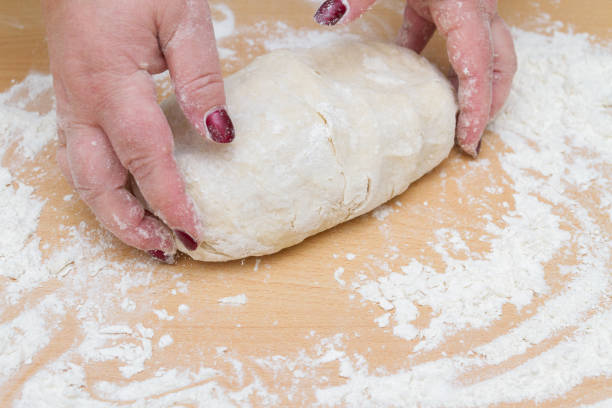 istock Kneading dough with flour on a wooden table at home 1221161282