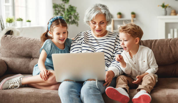 femme âgée heureuse avec des petits-enfants utilisant l’ordinateur portatif à la maison - 13431 photos et images de collection