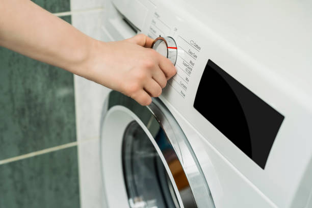 istock Close up of woman choosing cycle program on washing machine 1221162549