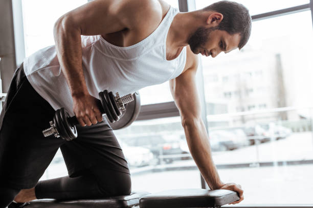 istock athletic man exercising with dumbbell in gym 1221164268
