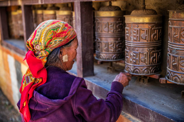 старая тибетская женщина поворота молитвенные колеса, верхний мустанг - prayer wheel стоковые фото и изображения