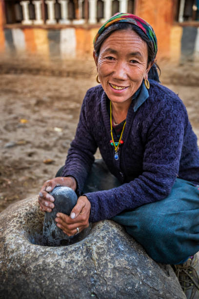 istock Tibetan woman using a stone mortar to make flour, Upper Mustang, Nepal 1221165941
