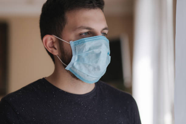 istock Man put on madical mask at home. Young man in protective mask. Coronavirus theme 1221170985