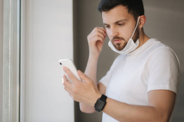 istock Young man take off protective mask and use smartphone. End of quarantine. Coronavirus theme 1221171802