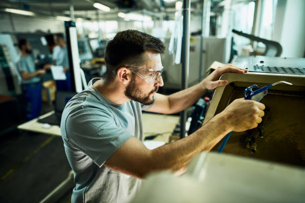 istock Young manual worker working with CNC machine in a factory. 1221173425