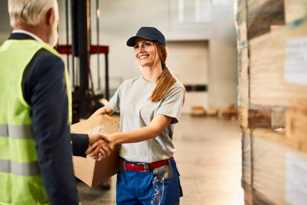 istock Happy female warehouse worker handshaking with senior businessman. 1221174005