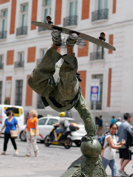 Madrid /Spain - July 20, 2019 - Street performer acting a bronze statue of a skateboarder showing skateboarding trick to amuse tourists in Puerta del Sol.