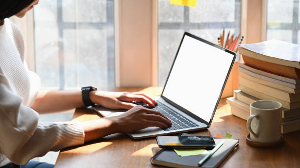 istock Cropped image of creative woman's hands typing on computer laptop that putting on wooden working desk and surrounded by stack of books, pencil holder, coffee cup and smartphone. Orderly workspace. 1221175879
