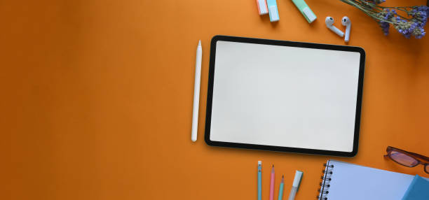 istock Top view image of white blank screen computer tablet, glasses, marker pens, pencils, notebook and flowers that putting together on colorful working desk. Orderly workspace concept. 1221176087