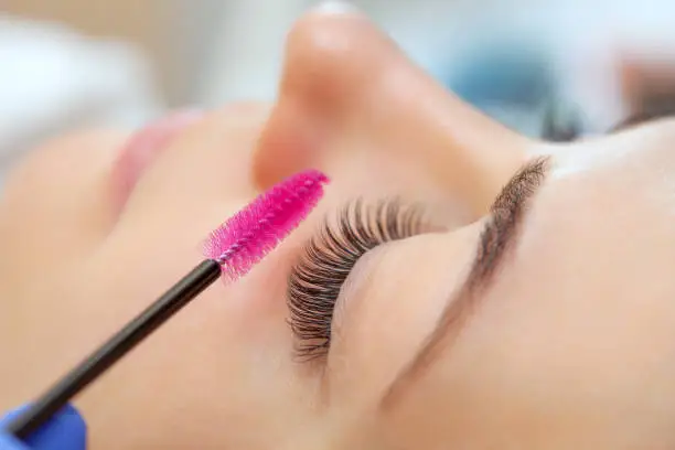 Photo of Eyelash extension procedure close up. Beautiful woman with long eyelashes in a beauty salon. Makeup concept
