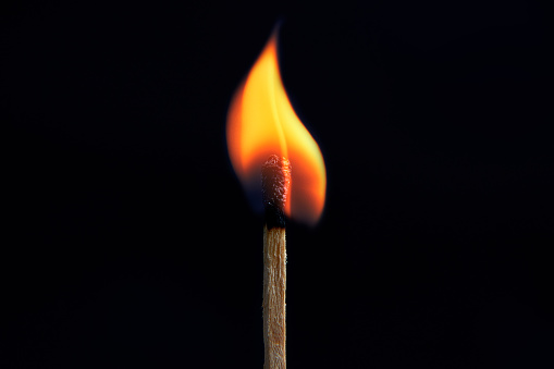 Close-up of igniting matchstick against black background.