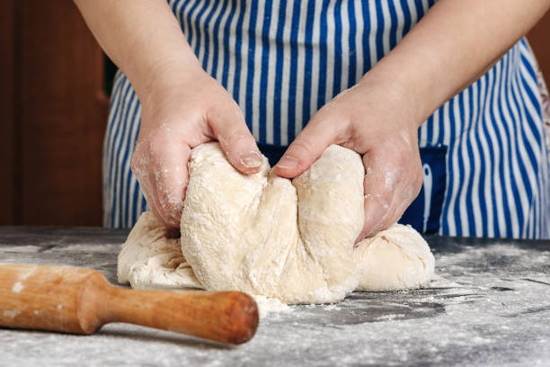 Female hands knead the dough on a floury table. Female hands knead the dough on a floury table. The concept of home cooking. baking bread photos stock pictures, royalty-free photos & images