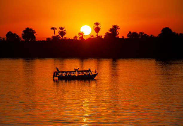 View across large wide river Nile in Egypt through rural countryside landscape with beautiful orange sunset