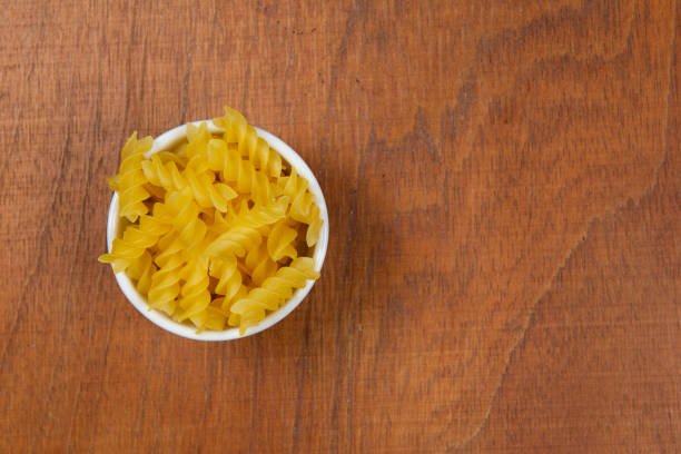 istock bowl with raw pasta on wooden background. 1221185799