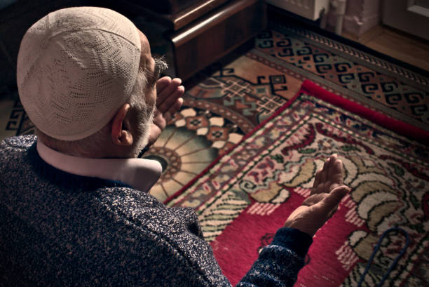 Very old Turkish Muslim man at his 80's praying to Allah at home on his rug stock photo