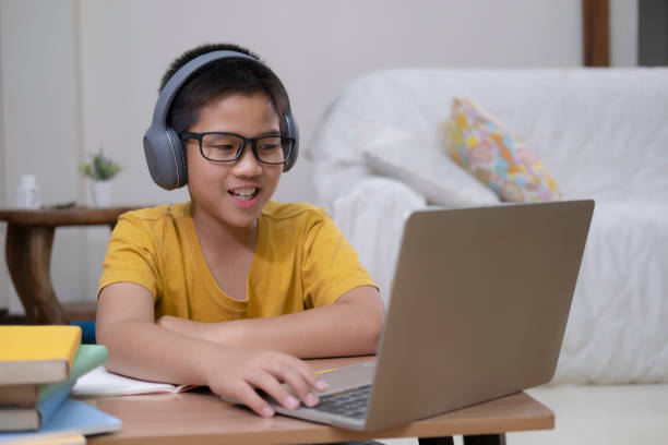 istock Young Boy Wearing Headphones and Using Laptop 1221191841