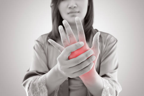 mujer asiática sosteniendo su mano contra fondo gris, concepto de dolor - rheumatic fotografías e imágenes de stock