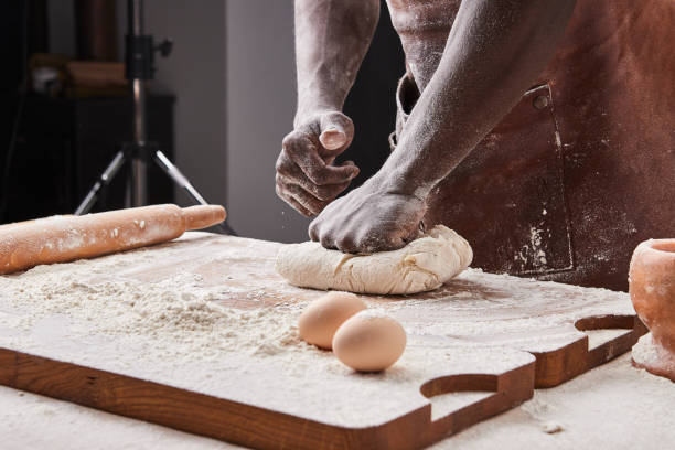 Dark skin baker man kneads Dough in the kitchen. Pastry chef prepares yeast dough for pizza pasta.
