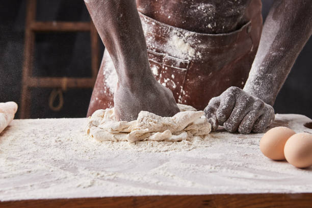 Dark skin baker man kneads Dough in the kitchen. Pastry chef prepares yeast dough for pizza pasta.