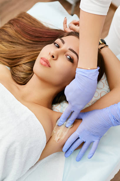istock Luxurious brunette while sugaring in a beauty salon. A beautician with gloves puts paste on the armpits of a young girl. 1221199877