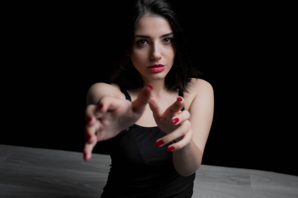 Young woman reaching out with her hand to camera. Portrait of woman on black background