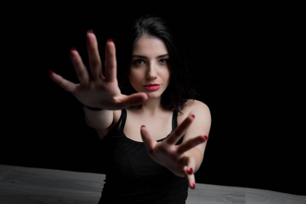 Young woman reaching out with her hand to camera. Portrait of woman on black background