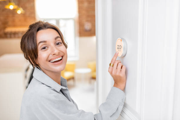 istock Woman regulating heating temperature with a smart thermostat 1221200805