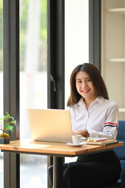 istock Portrait woman smiling and keep hand on chin while sitting in front her computer laptop at the wooden working desk over comfortable living room as background. 1221202248