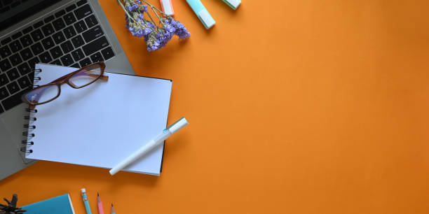istock Top view image of computer laptop putting on colorful working desk surrounded by notebook, glasses, pen, flowers, marker pens and pencil. Orderly workspace concept. 1221202403