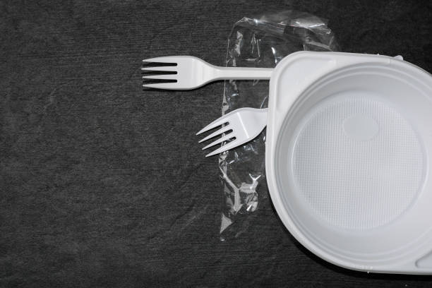 istock White plastic forks, plate and packages on a gray-black dark background. Plastic waste. Environmental concept. Ban single use plastic. Anti ecology and pollution of the planet 1221204145