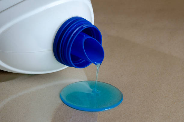 Gel for washing clothes is poured. White plastic canister with washing gel dropped. Homemade routine. Household chemicals. Selective focus.