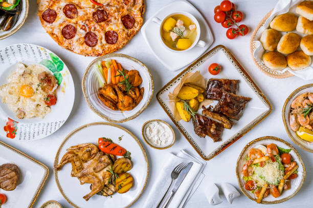 istock Assorted dishes on table. Barbecue pork ribs, chicken wings, pasta carbonara, pizza pepperoni, fish soup, chicken tabaka, steak file minion and caesar with shrimps. 1221206443