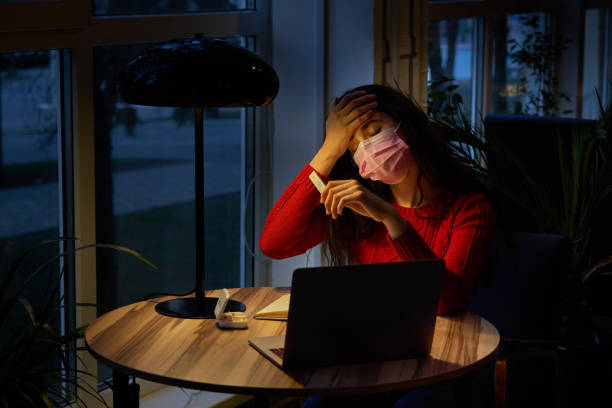 istock sick woman with pills and thermometer on a table working on a laptop from home on quarantine isolation 1221207477