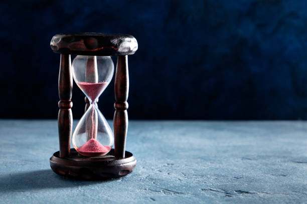 istock Time concept. An hourglass with sand falling through, on a dark background with copy space 1221210233