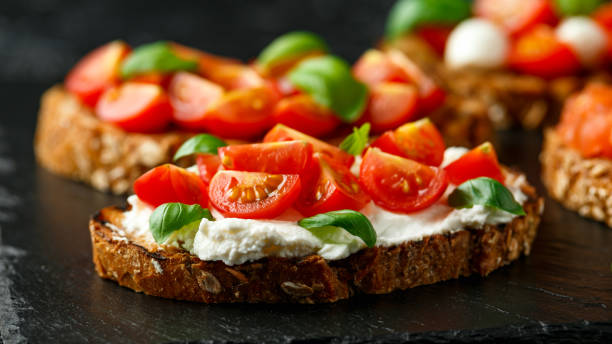 istock Bruschetta with ricotta cheese, basil, cherry tomato on rustic stone board 1221210394