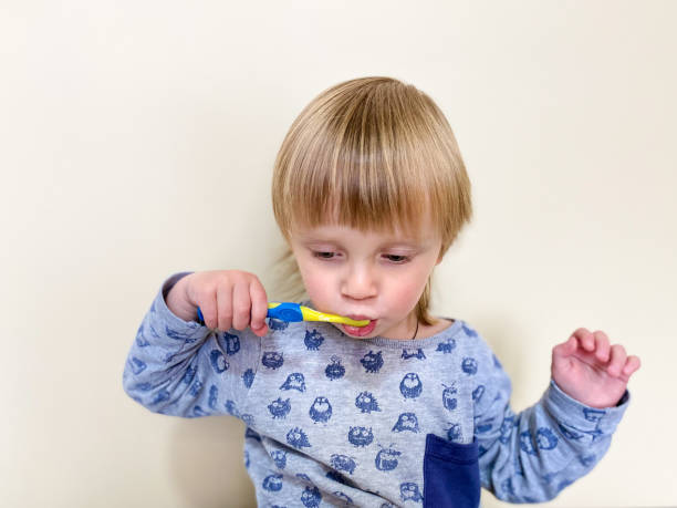 istock Little fair-skinned child brushing his teeth, on a light background. 1221210450