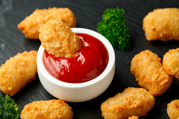 istock Crispy Battered scampi nuggets with ketchup and mayonnaise on rustic stone board. 1221210707