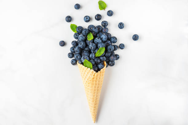 istock Food composition. Fresh summer blueberries with mint in waffle ice cream cone on white background. top view 1221210770