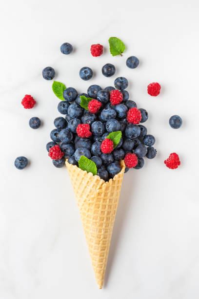 istock wild berries blueberry and raspberry with mint in waffle ice cream cone on white marble background. top view. flat lay 1221210803