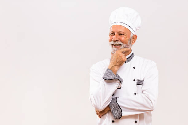 istock Portrait of senior chef thinking  on gray background. 1221212089