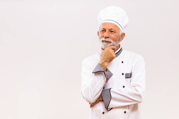 istock Portrait of senior chef thinking  on gray background. 1221212204