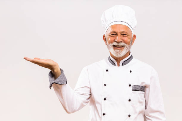istock Senior chef showing palm of hand 1221212393