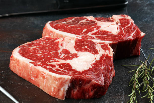 Steak. Two fresh raw rib-eye steak with rosmary in a rustic style table