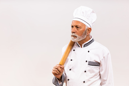 Chef holding wooden spoon on black background