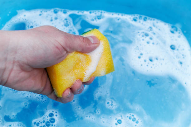 istock yellow sponge in hand on a blue background, soap foam 1221214283