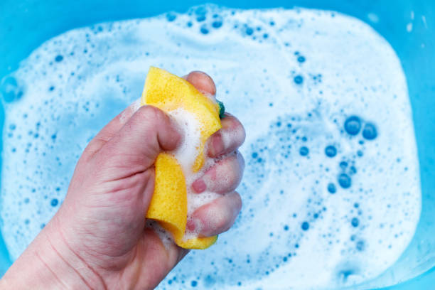 istock yellow sponge in hand on a blue background, soap foam 1221214288
